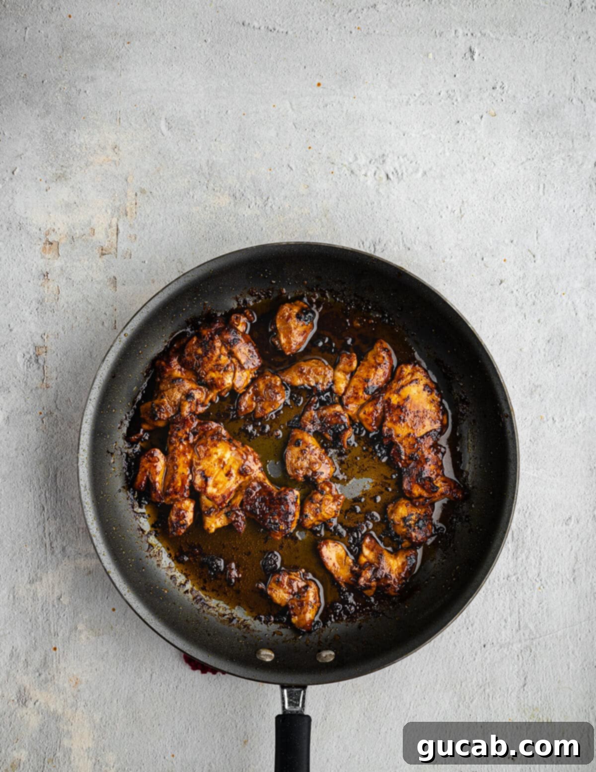 Caramelized honey chipotle chicken thighs cooking in a hot nonstick skillet, achieving a beautiful sear.