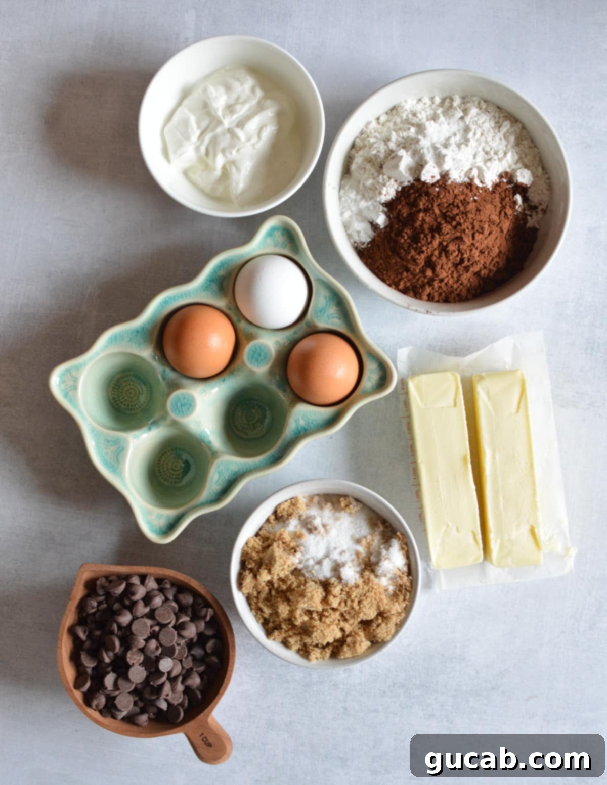 Decadent Gluten-Free Chocolate Pound Cake 3 Individual ingredients for gluten-free chocolate pound cake: sour cream, gluten-free flour, Dutch cocoa powder, eggs, butter, brown sugar, white sugar, and semisweet chocolate chips.