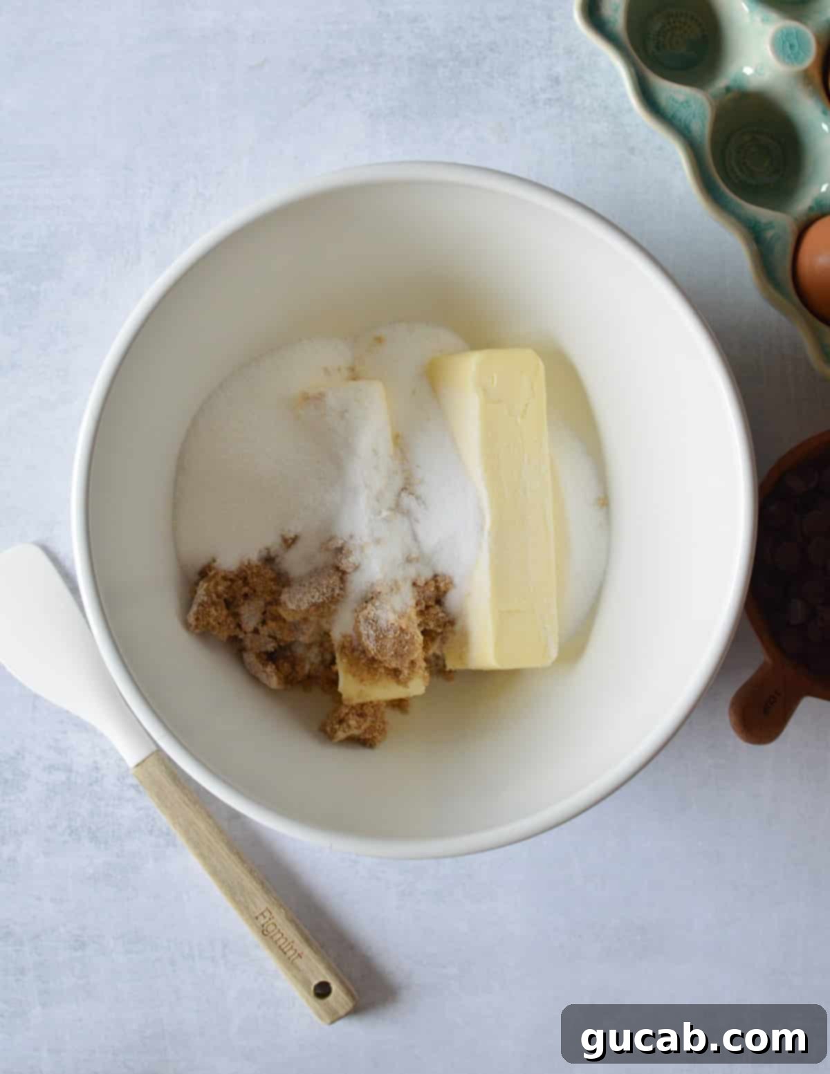 Close-up of butter, granulated sugar, and brown sugar in a large mixing bowl, ready to be creamed.