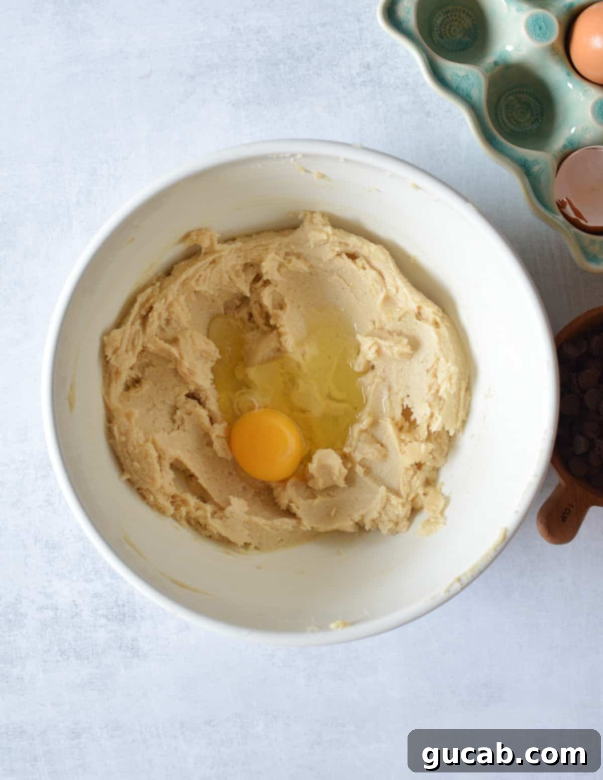 A bowl of creamed butter and sugar with a single egg placed on top, ready to be mixed in.