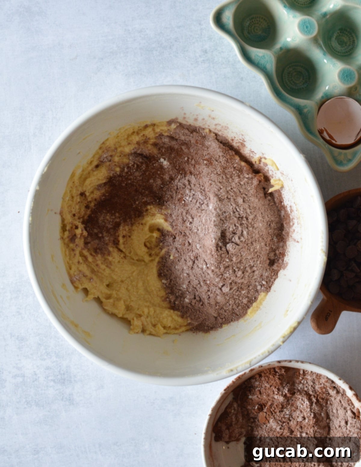 Decadent Gluten-Free Chocolate Pound Cake 8 A mixing bowl with creamed butter, sugar, and egg, topped with gluten-free flour mixture, ready to be combined.