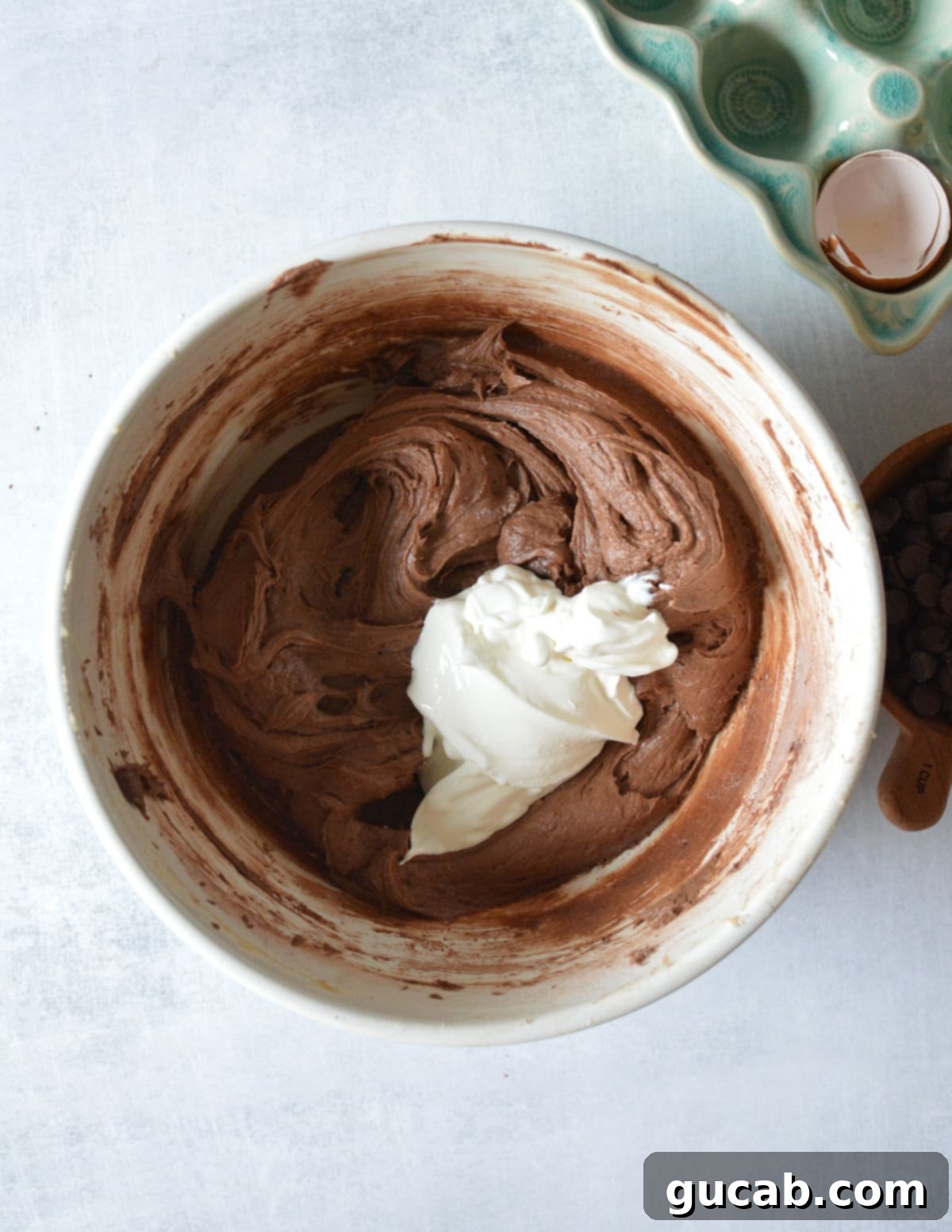 Decadent Gluten-Free Chocolate Pound Cake 9 A bowl of thick gluten-free chocolate batter with a dollop of sour cream on top, ready to be mixed.
