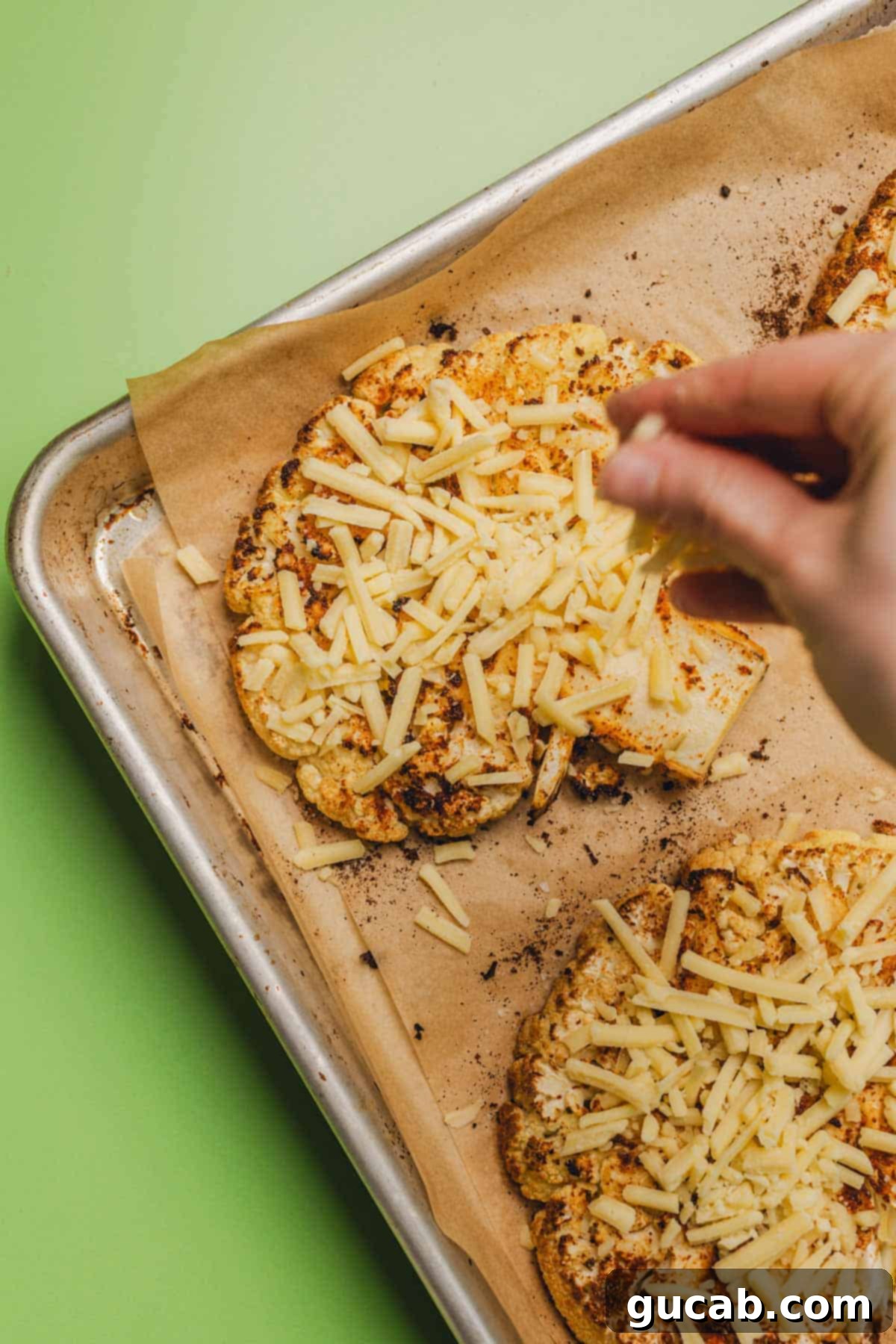 sprinkling shredded gouda cheese on roasted cauliflower steaks 