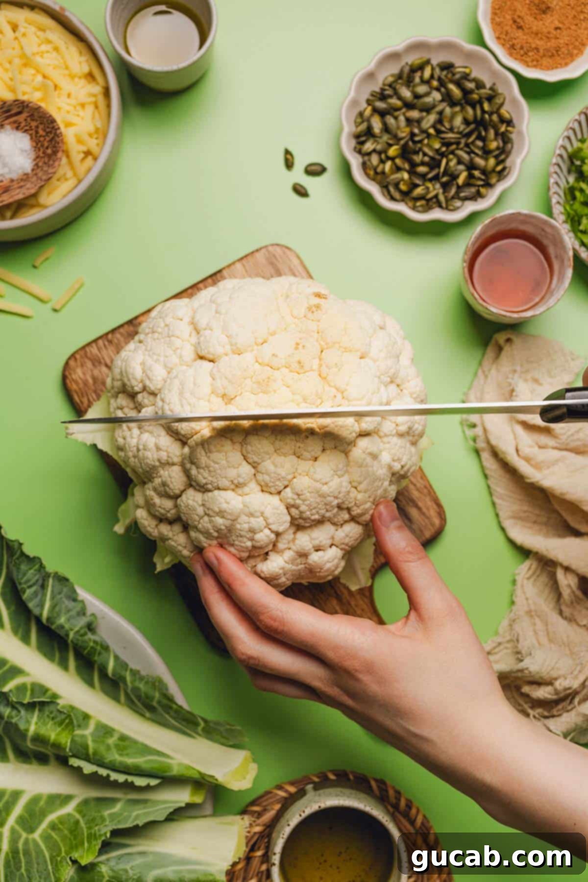 hand holding a head of cauliflower while cutting into the top of it. 