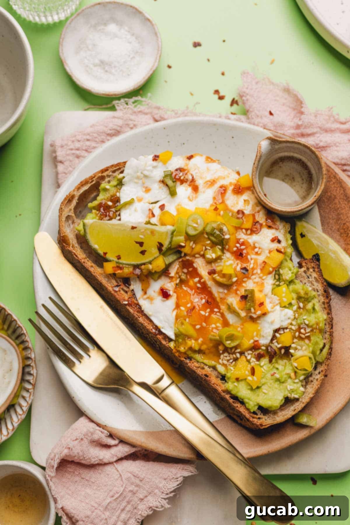 avocado toast with a fried egg, honey chipotle sauce, and pickled bell pepper on top. 