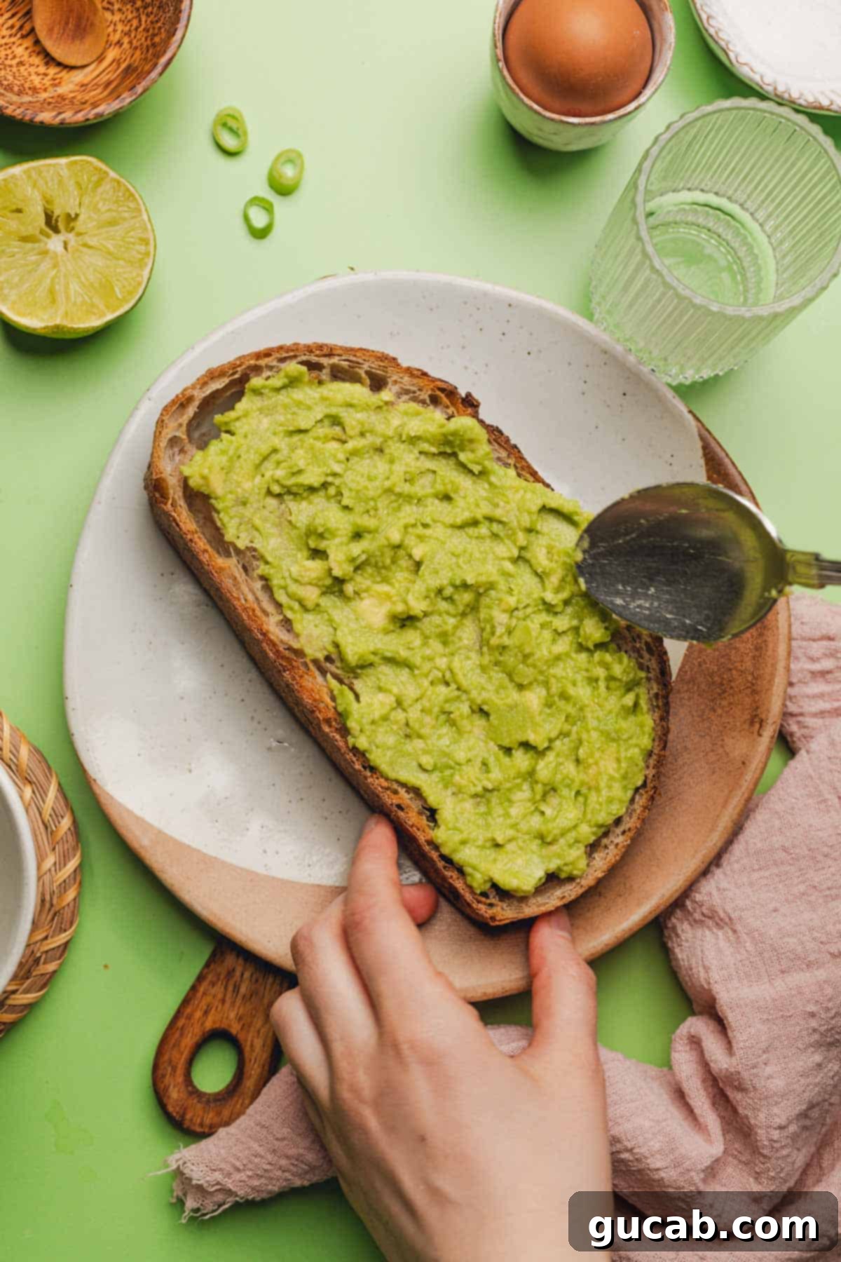 Mashed avocado generously spread across a golden-brown slice of toasted sourdough bread.