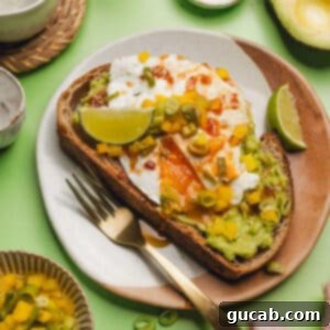 avocado toast on a plate with fried egg, chipotle sauce, and pickled bell peppers.