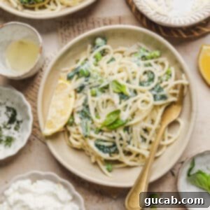 A plate with lemon ricotta pasta with a fork and lemon wedge, showcasing the final dish.