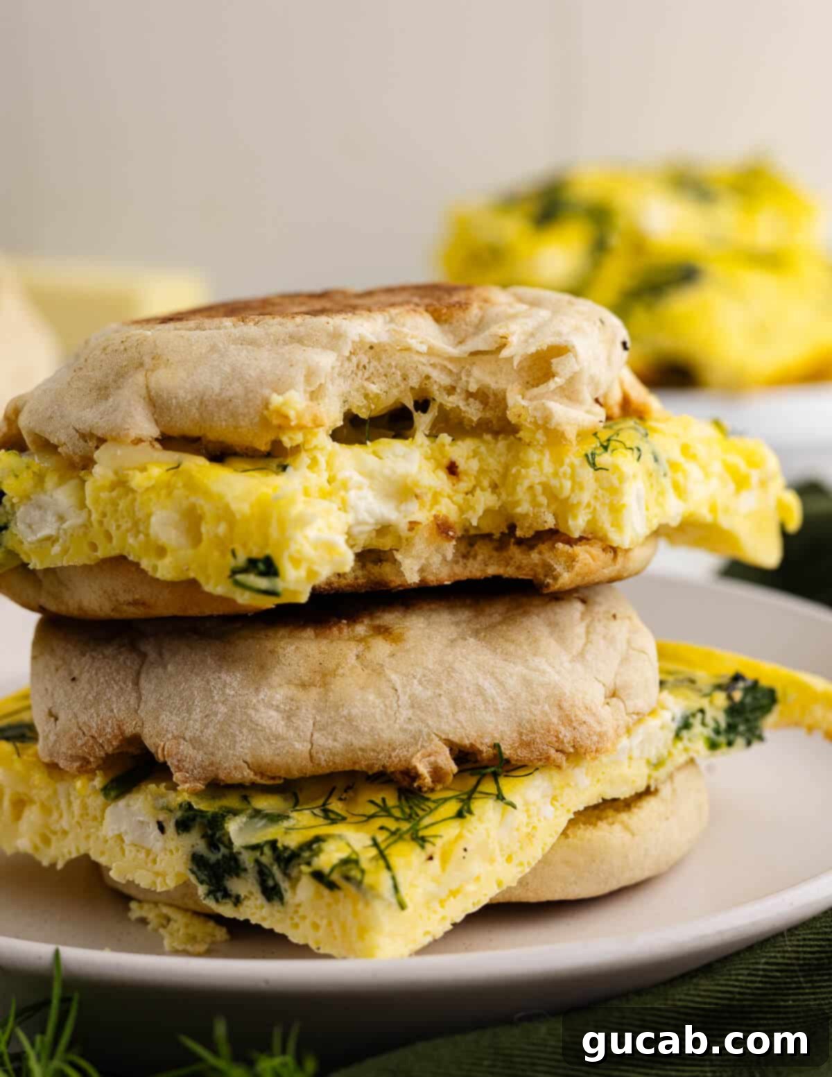 two egg sandwiches stacked on a plate. 