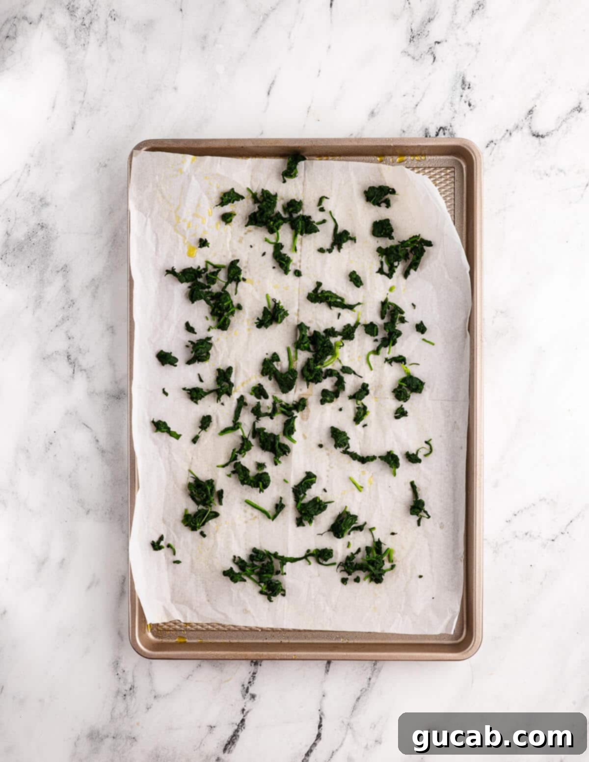 cooked spinach on parchment paper in a sheet pan. 