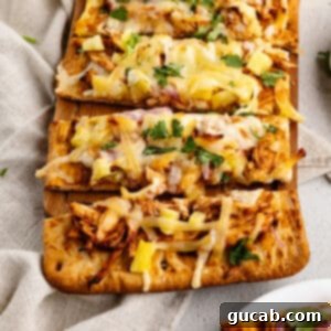 A top-down view of a freshly baked BBQ chicken flatbread pizza, featuring melted cheese, juicy chicken, pineapple, and fresh cilantro garnish, ready to be sliced.
