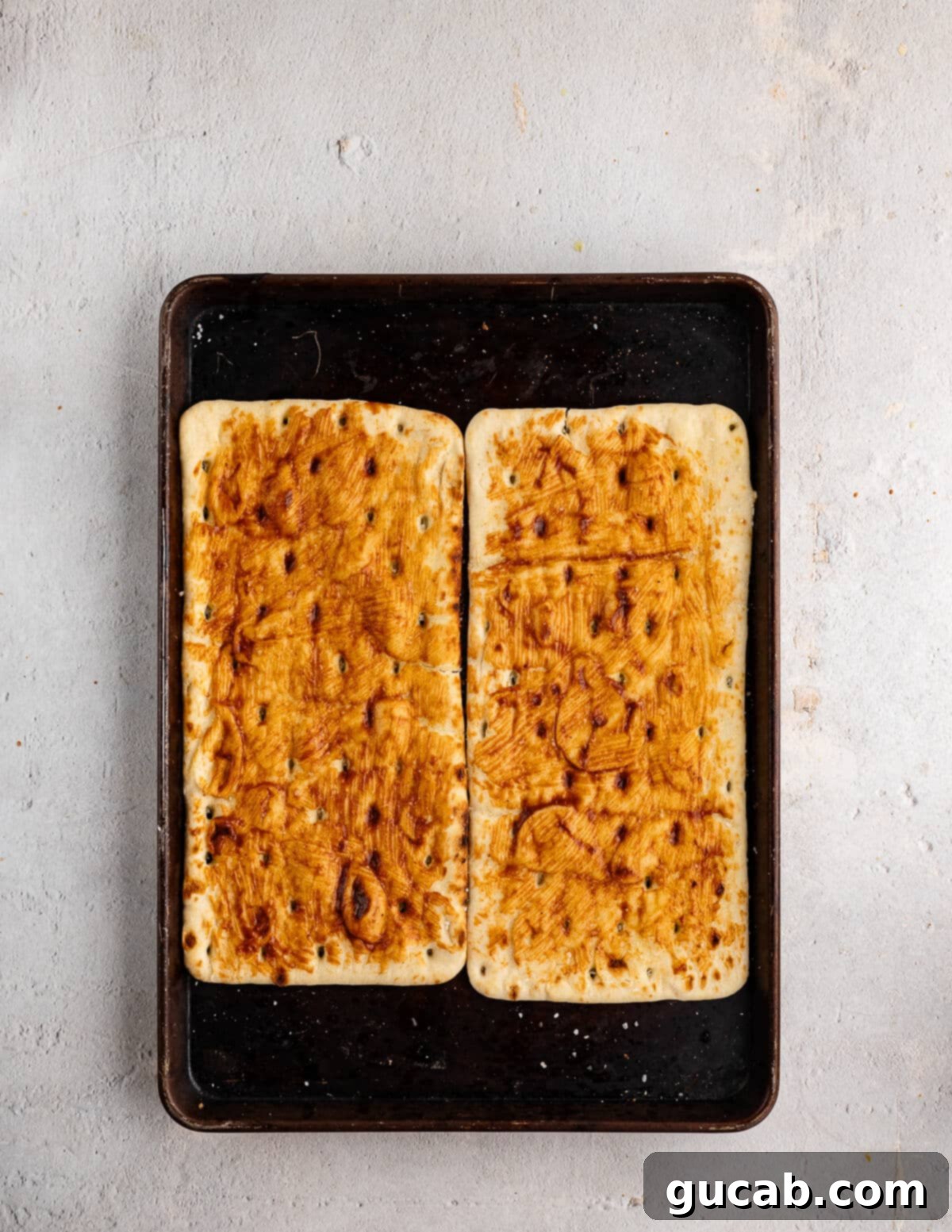 Par-baked flatbreads on a sheet pan, lightly seasoned and pre-cooked, ready for the next layer of toppings.