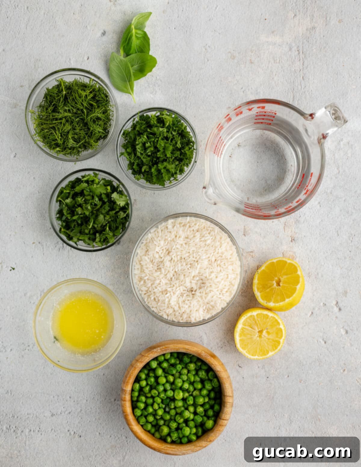 Arrangement of white rice, fresh herbs, lemon, butter, peas, and water on a rustic surface.