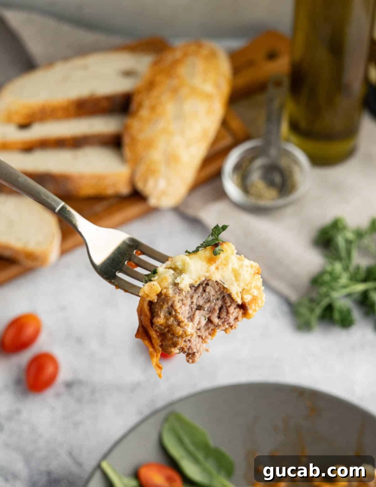 One-Pan Cheesy Meatballs 14 A fork piercing a meatball, with a bite taken out to reveal the tender, juicy interior and a string of melted cheese.