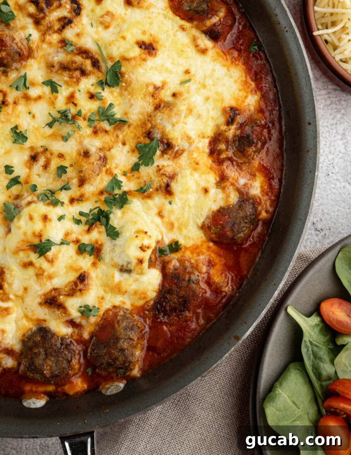 One-Pan Cheesy Meatballs 4 Saucy meatballs in an oven-safe skillet with a generous layer of melted cheese and creamy ricotta on top, ready to be served.