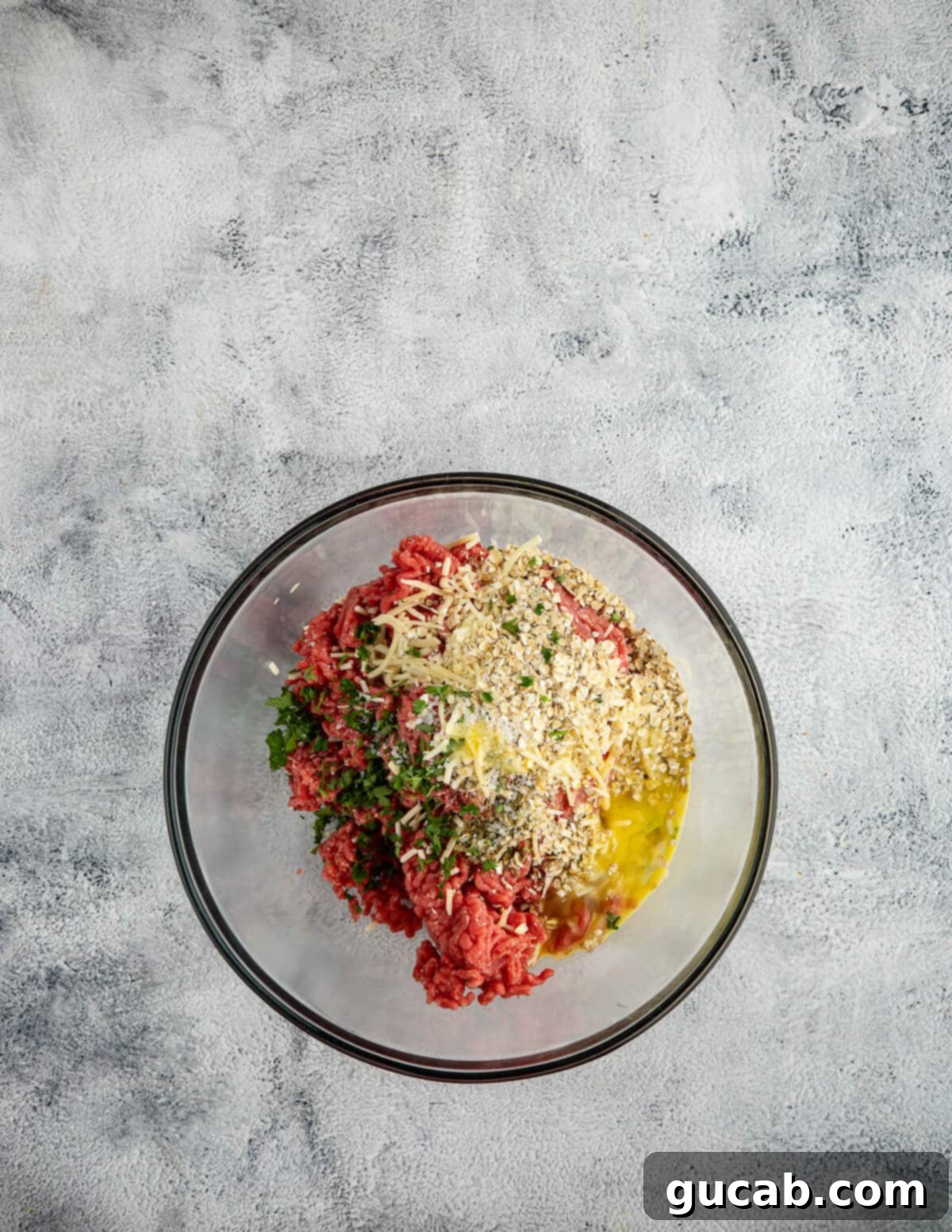 One-Pan Cheesy Meatballs 5 a bowl of ground beef, oats, parsley, egg, and spices.