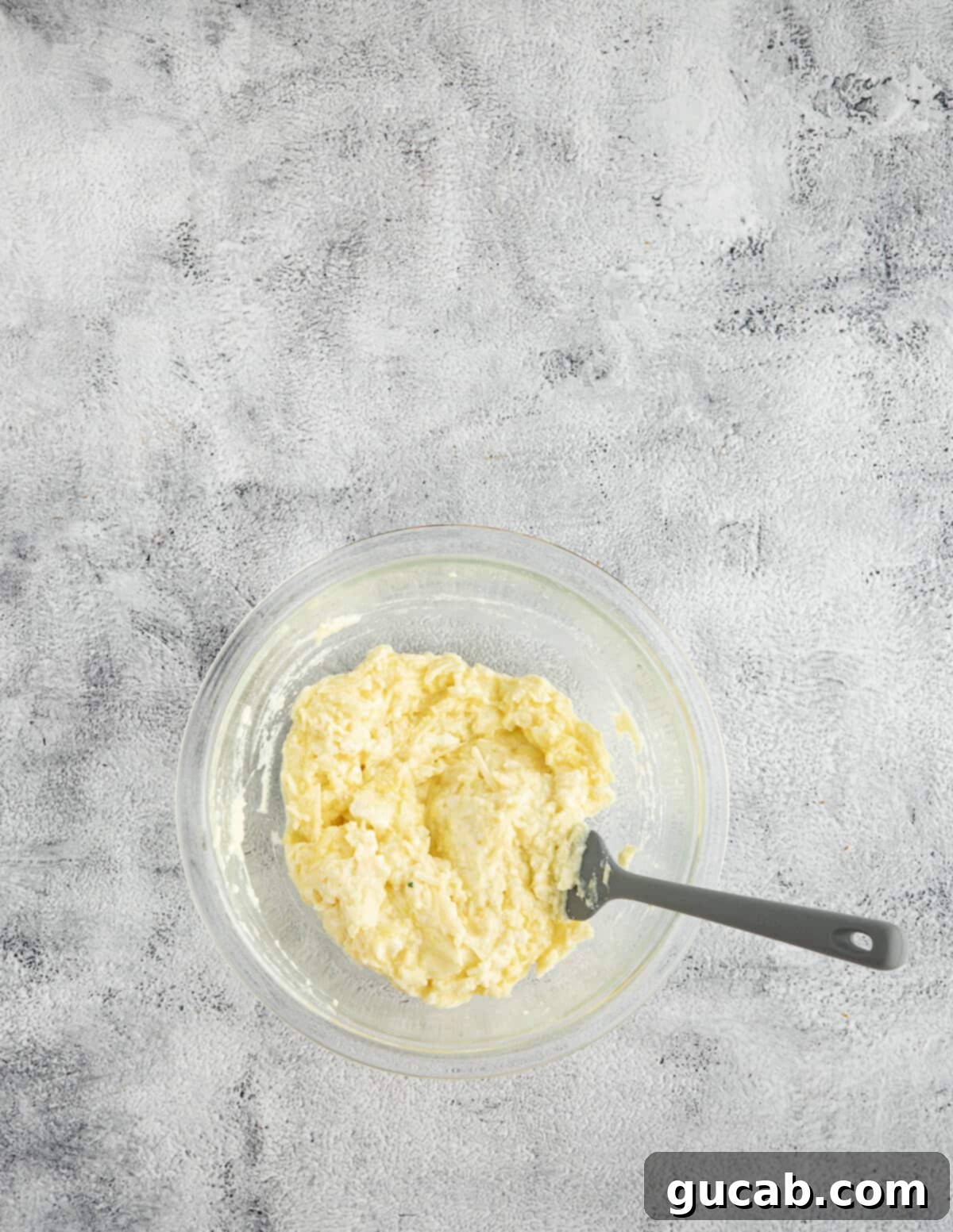 One-Pan Cheesy Meatballs 7 A bowl of creamy ricotta cheese thoroughly mixed with egg and shredded cheese, forming the cheesy topping.
