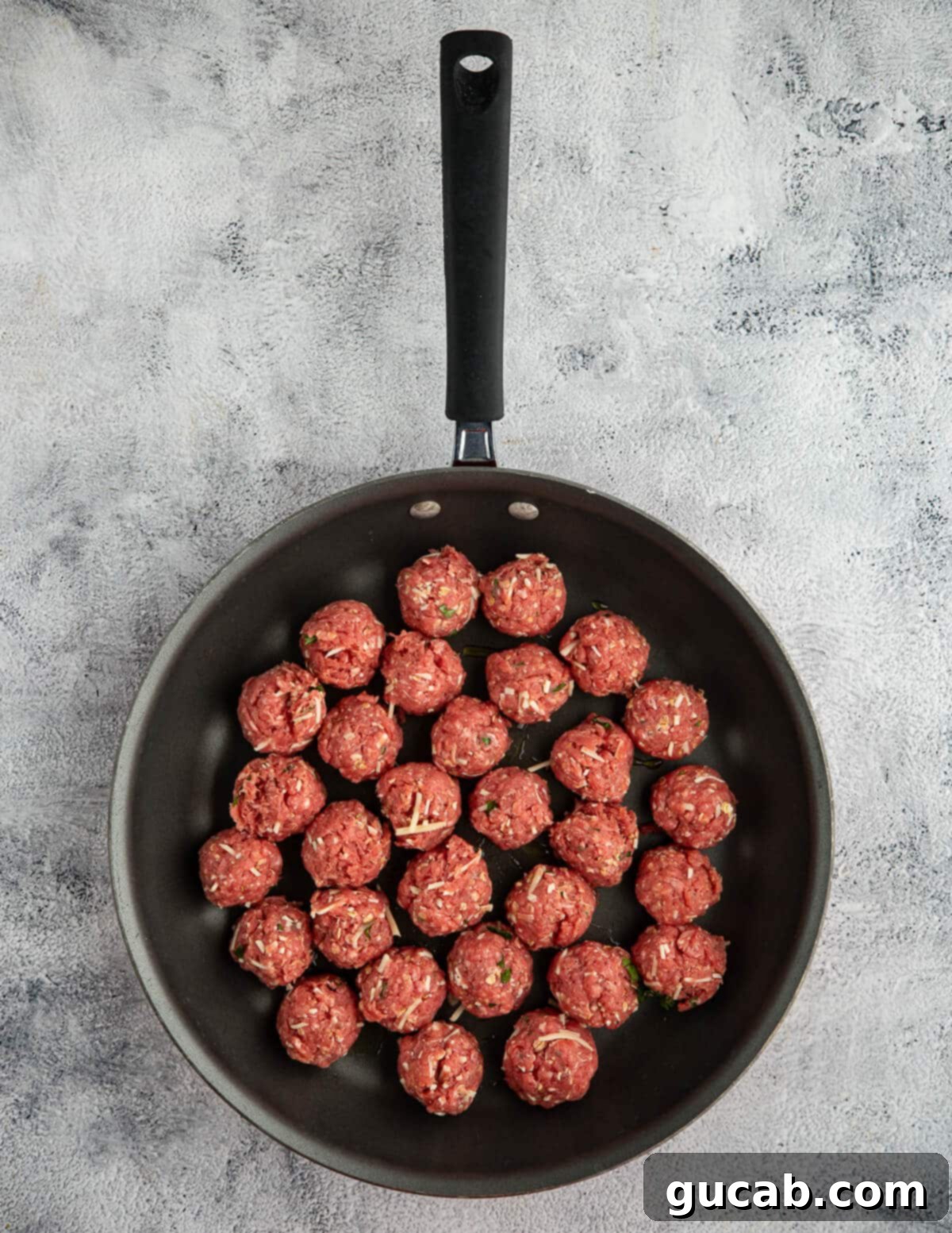 One-Pan Cheesy Meatballs 8 Raw, unbrowned meatballs neatly arranged in a single layer within a skillet, ready for cooking.