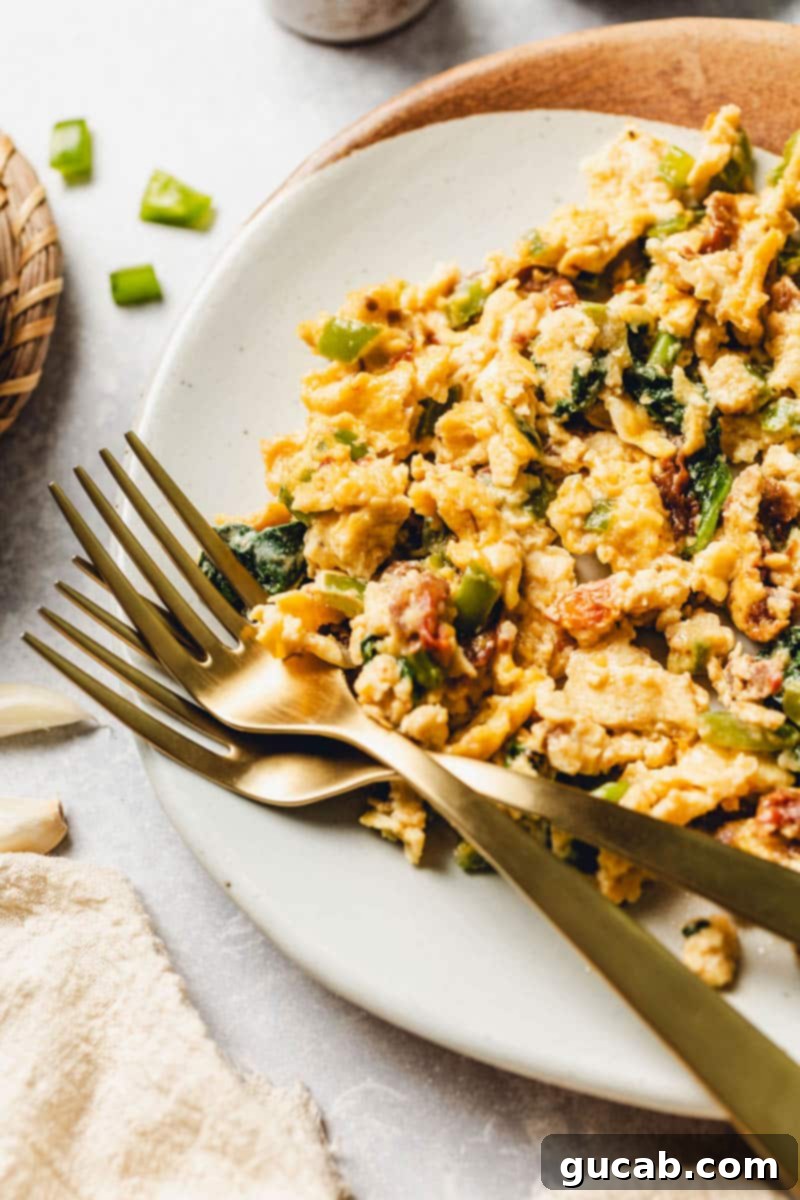 scrambled eggs with veggies on a plate with forks.