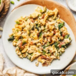 a plate of scrambled eggs with spinach and cheese