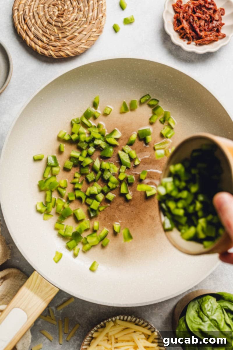 hand pouring diced bell pepper into a skillet.