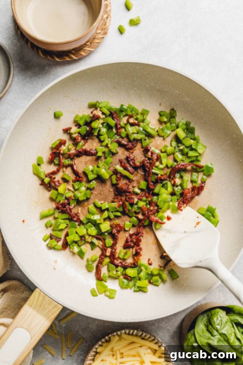 diced bell pepper and sun-dried tomatoes in a skillet.