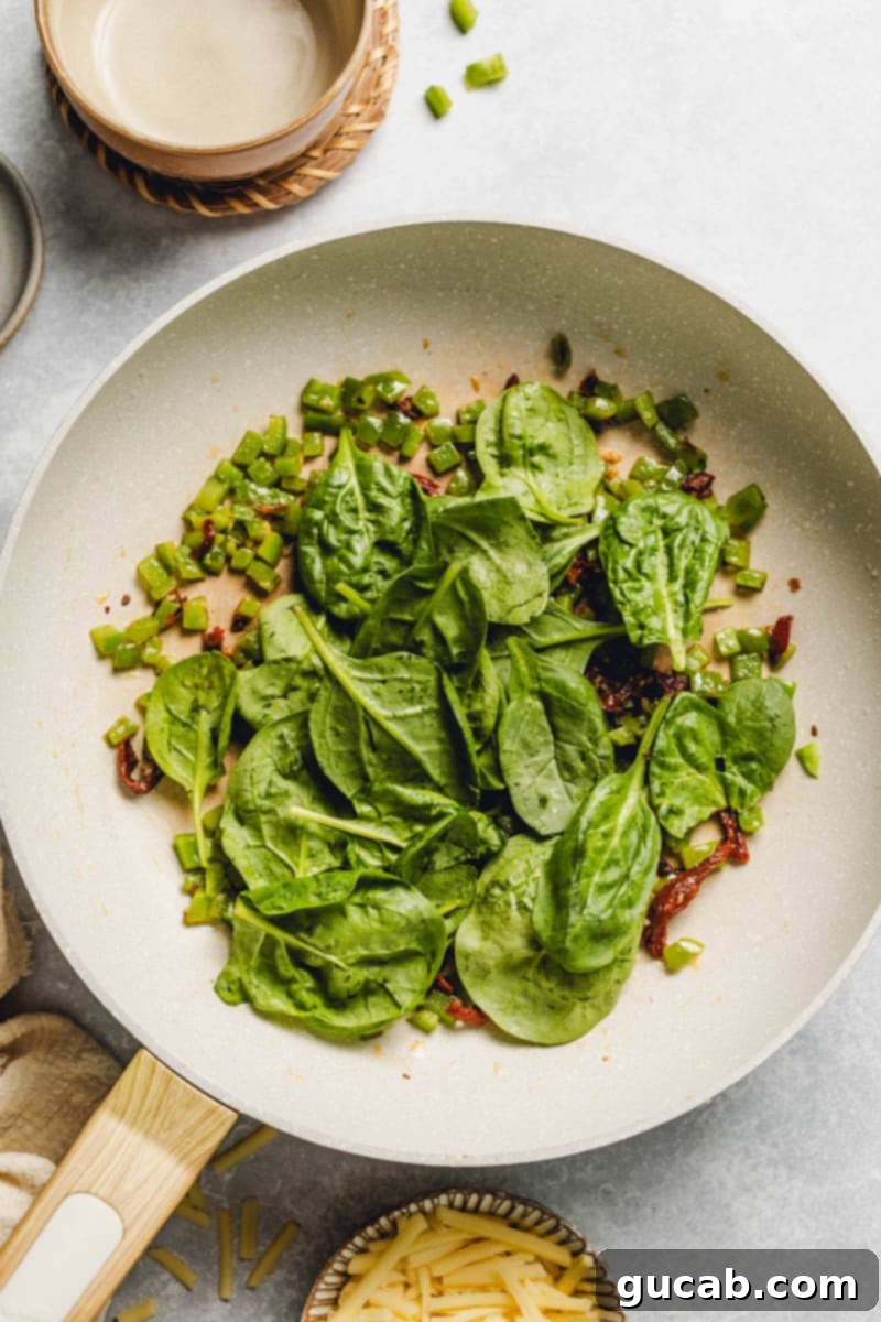 bell pepper, sun-dried tomatoes, and spinach in a skillet.