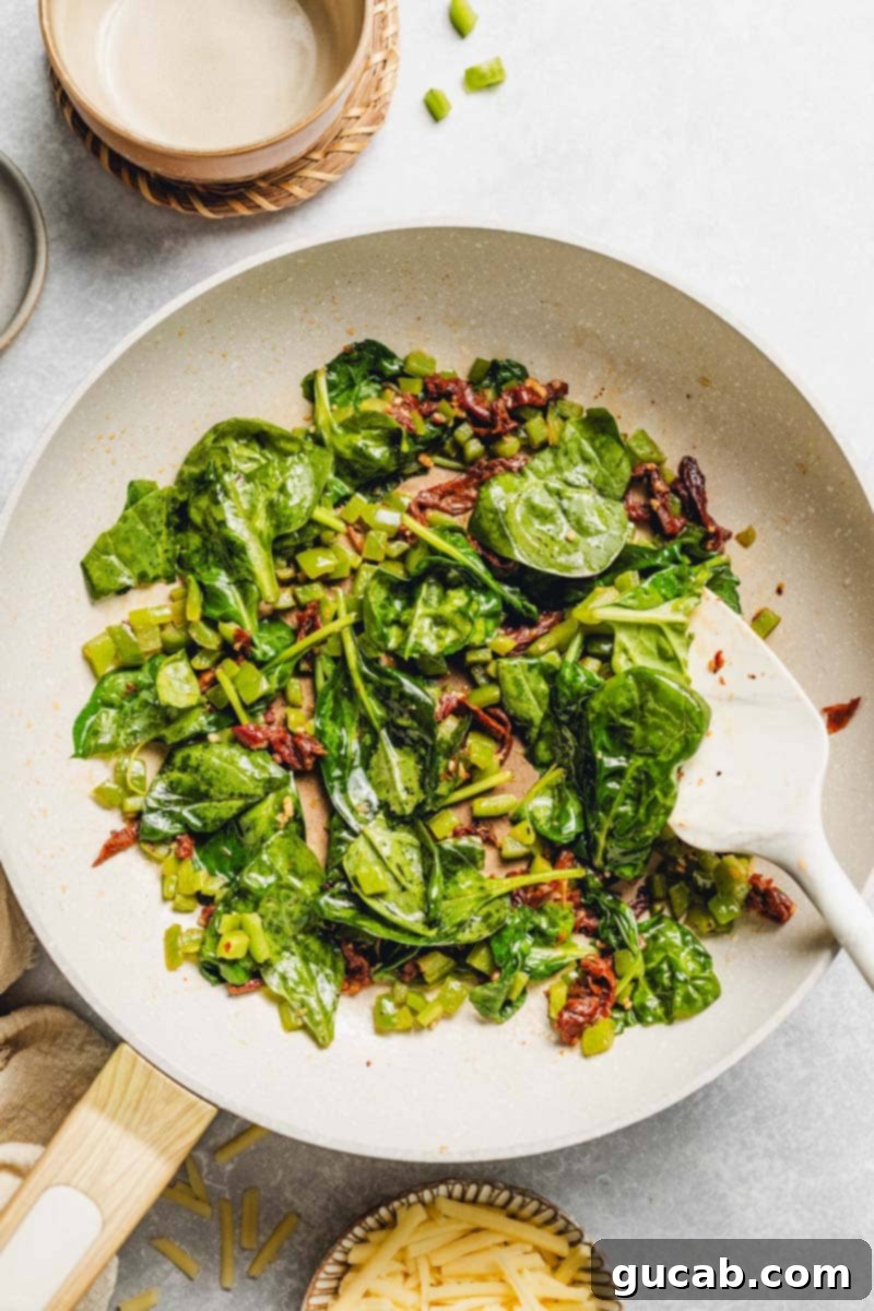 wilted spinach, bell pepper, and sun-dried tomatoes in a skillet.