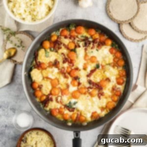 The Ultimate Date Night Chicken Meatballs 16 A skillet with chicken meatballs in a creamy sauce with tomatoes, garnished with fresh herbs.