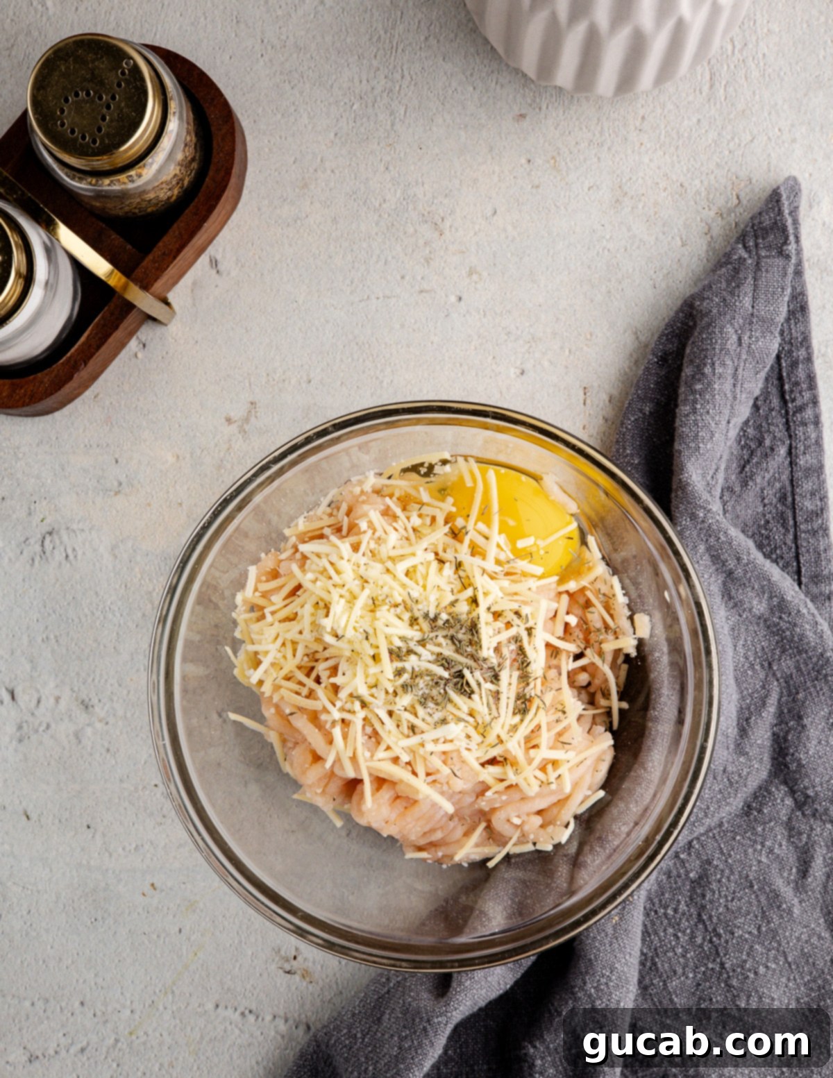 a bowl with ground chicken, egg, parmesan, spices, and oats. 