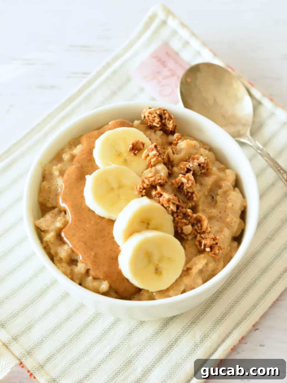 A beautifully prepared bowl of oatmeal topped with creamy peanut butter, perfectly sliced banana, and crunchy granola, ready to be enjoyed.