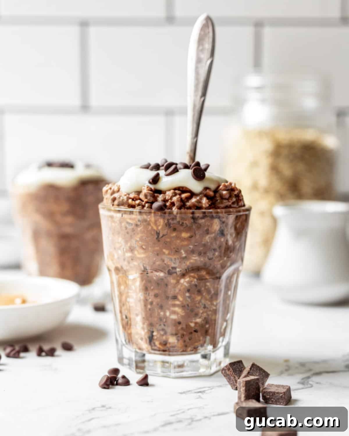 A clear glass jar brimming with layers of rich chocolate peanut butter overnight oats, showcasing its creamy texture and delicious blend of flavors.