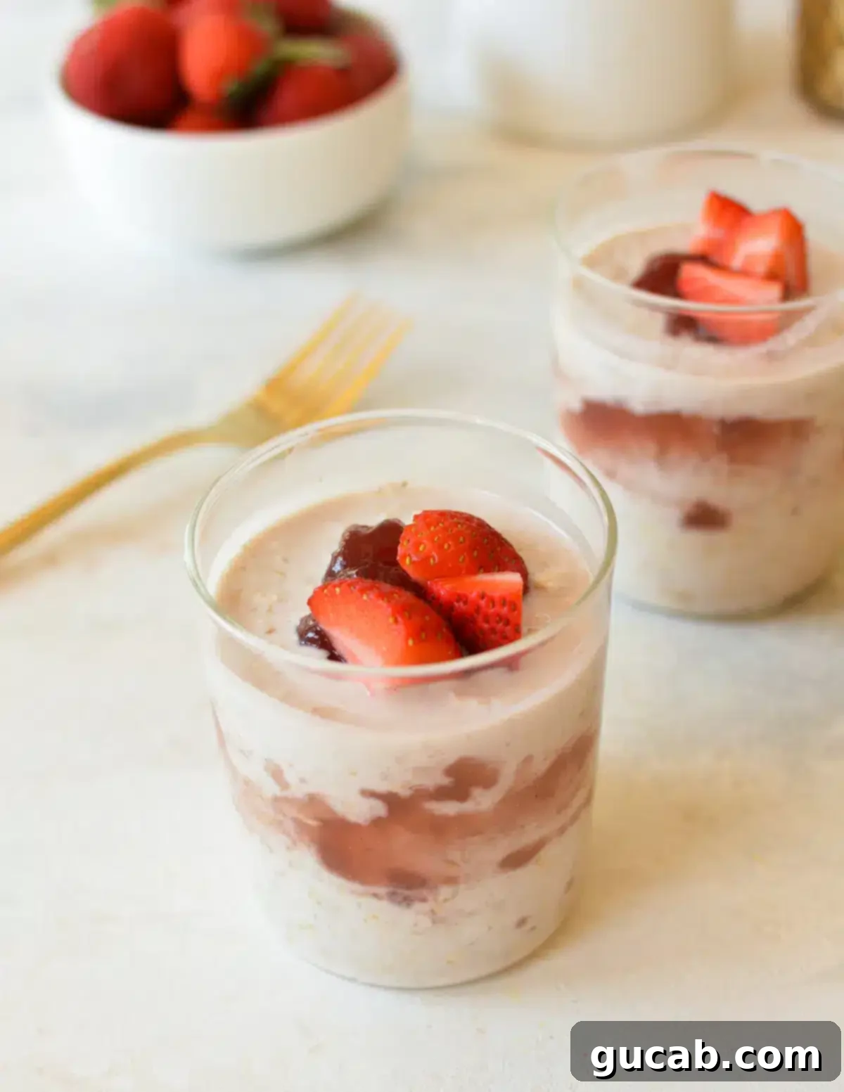 Jars of overnight oats featuring layers of raspberry jam and fresh raspberries, creating a visually appealing and fruity breakfast.