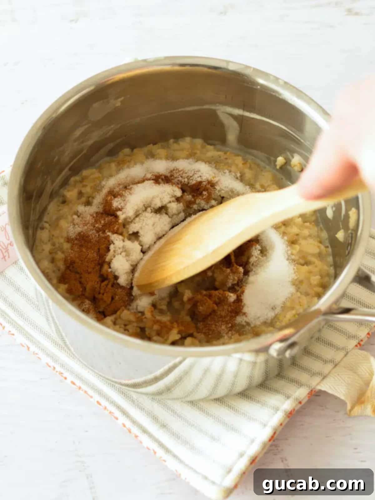 A wooden spoon gently stirring a bowl of warm oatmeal, beautifully enhanced with sprinkles of rich brown sugar and aromatic cinnamon.