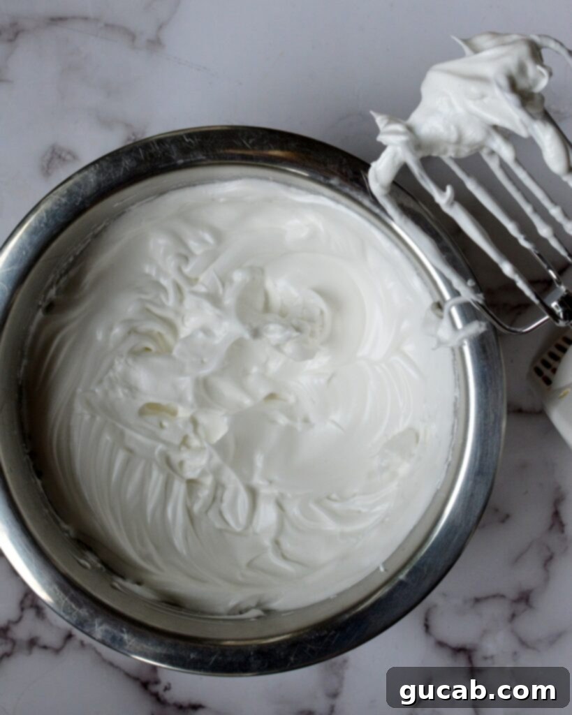 perfectly whipped egg whites forming stiff peaks on a whisk