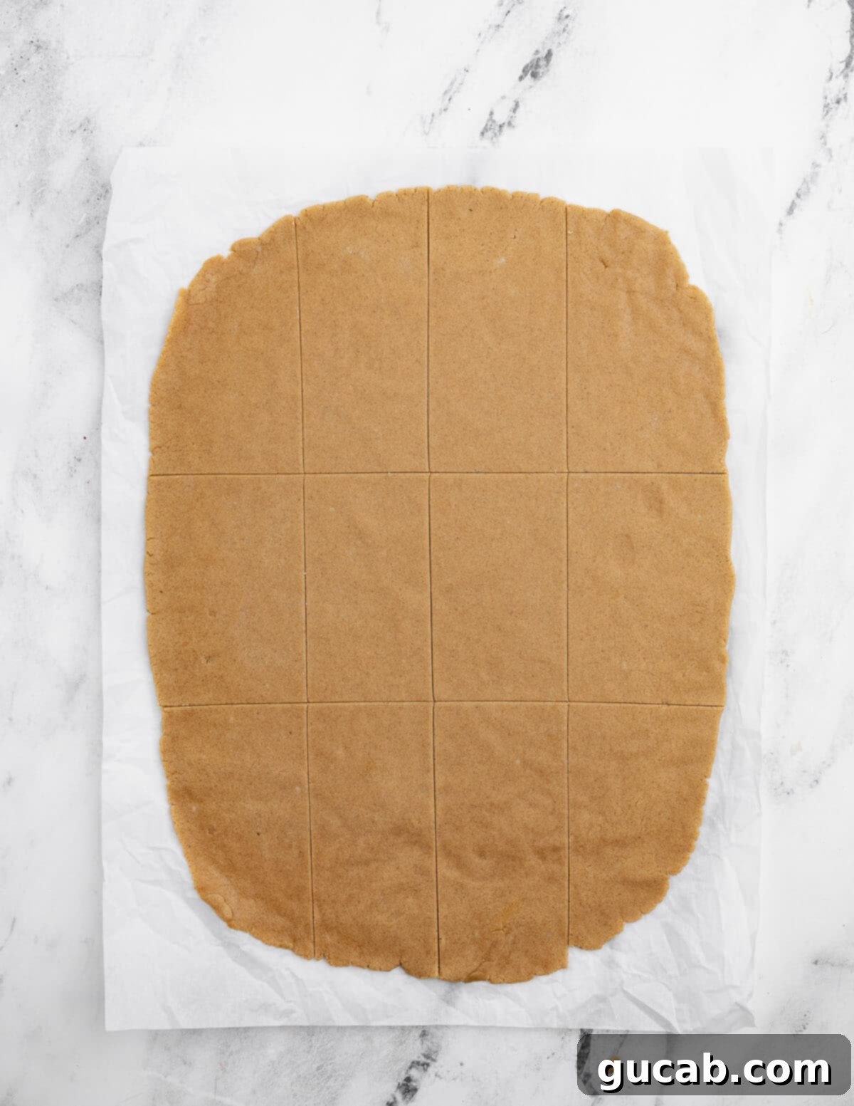 Golden Gluten-Free Graham Delights 11 rolled out gluten-free graham cracker cookie dough on parchment paper, showing its thinness.