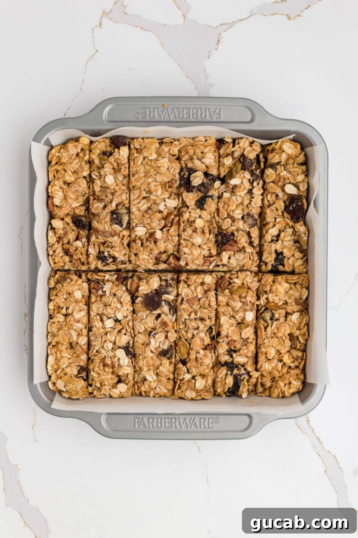 Neatly cut granola bars arranged in a square baking pan, showing they've firmed up perfectly after their first chilling stage.