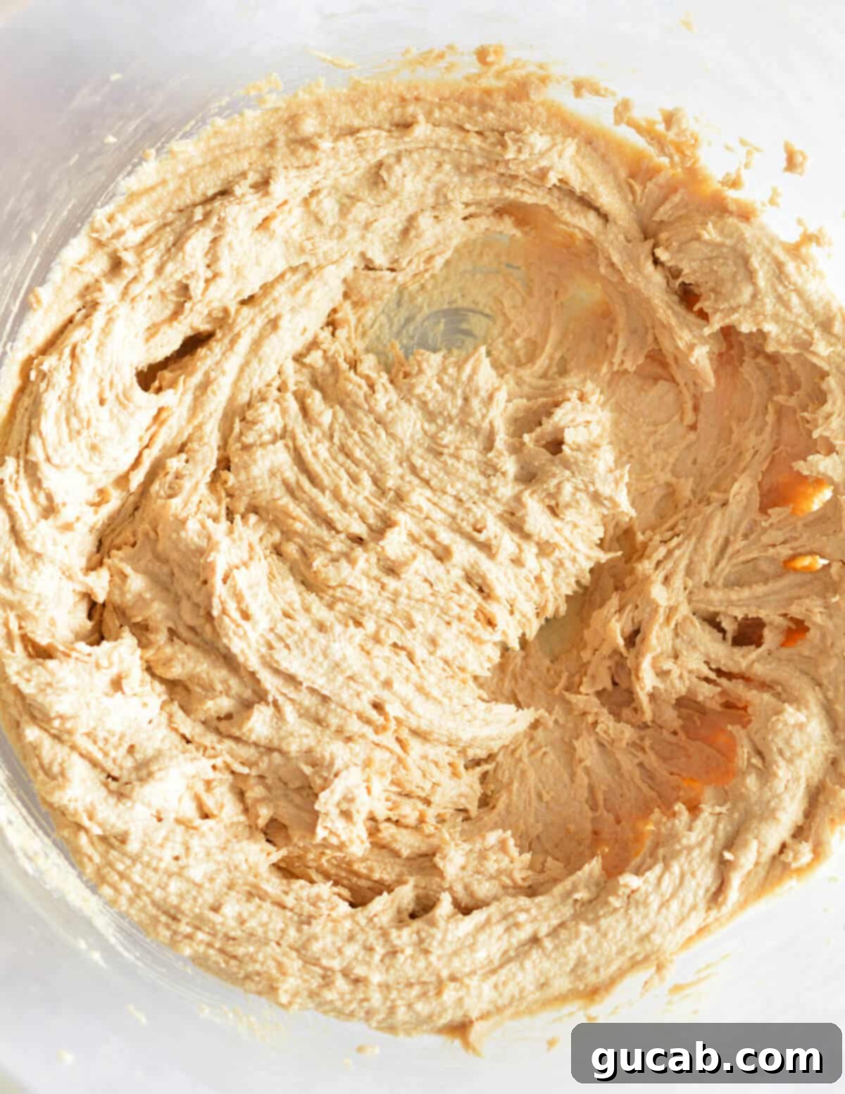 A close-up of the creamed mixture of butter, peanut butter, and sugars, showing its pale and fluffy texture after mixing.