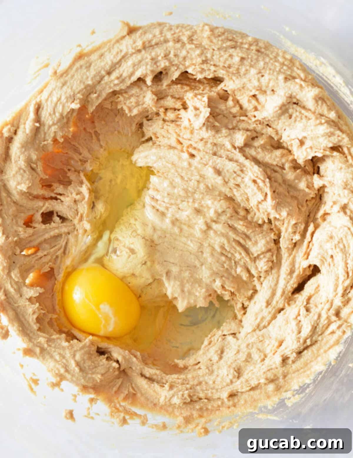 The creamed butter, peanut butter, and sugar mixture with a single egg added on top, ready to be mixed.
