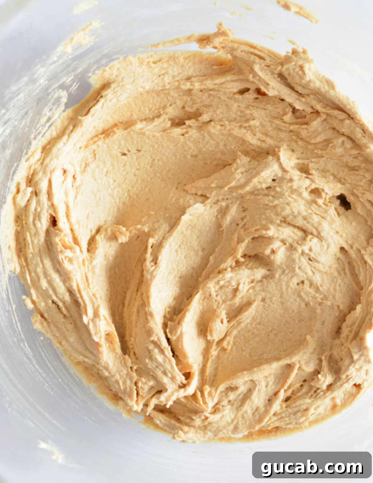 A bowl containing the fully incorporated mixture of creamed butter, sugars, peanut butter, and egg.