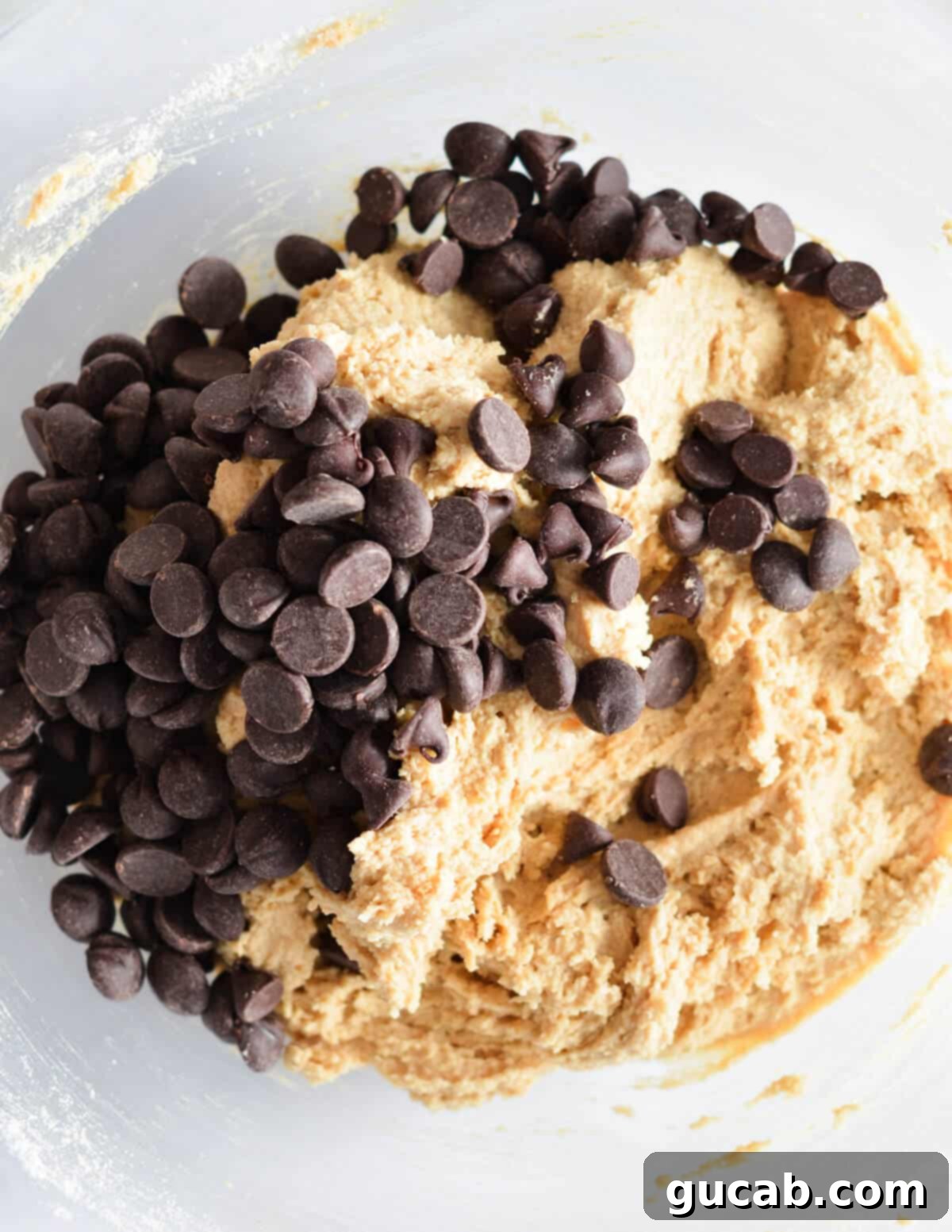 A bowl of peanut butter cookie dough with semisweet chocolate chips sprinkled on top, ready for the final mix.