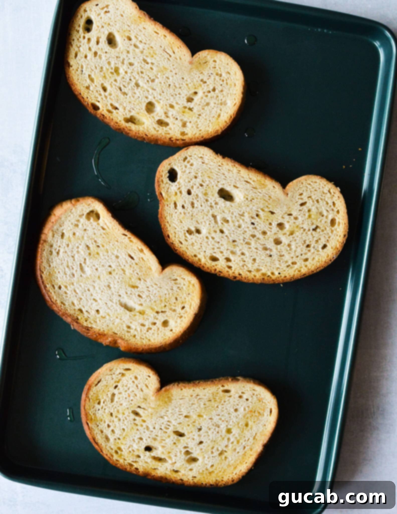 Raw sourdough bread slices arranged on a sheet pan, ready for toasting.