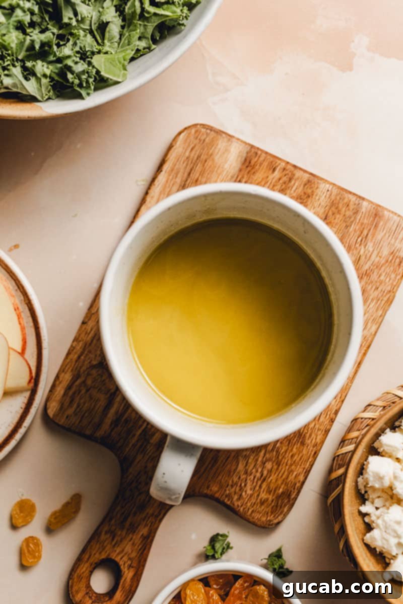 A cup of freshly made, creamy maple vinaigrette, ready to be drizzled over the salad.