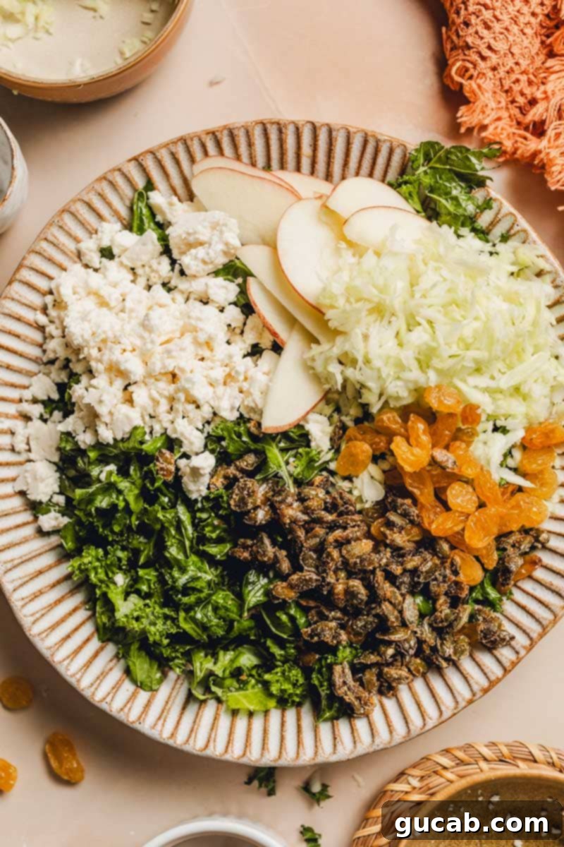 A large plate or bowl containing a base of massaged kale and shredded cabbage, ready for additional toppings.