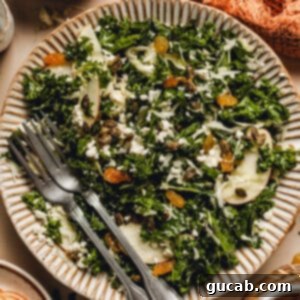 A vibrant kale salad featuring crisp apples, golden raisins, and crunchy maple pepitas, all drizzled with a delicious dressing.