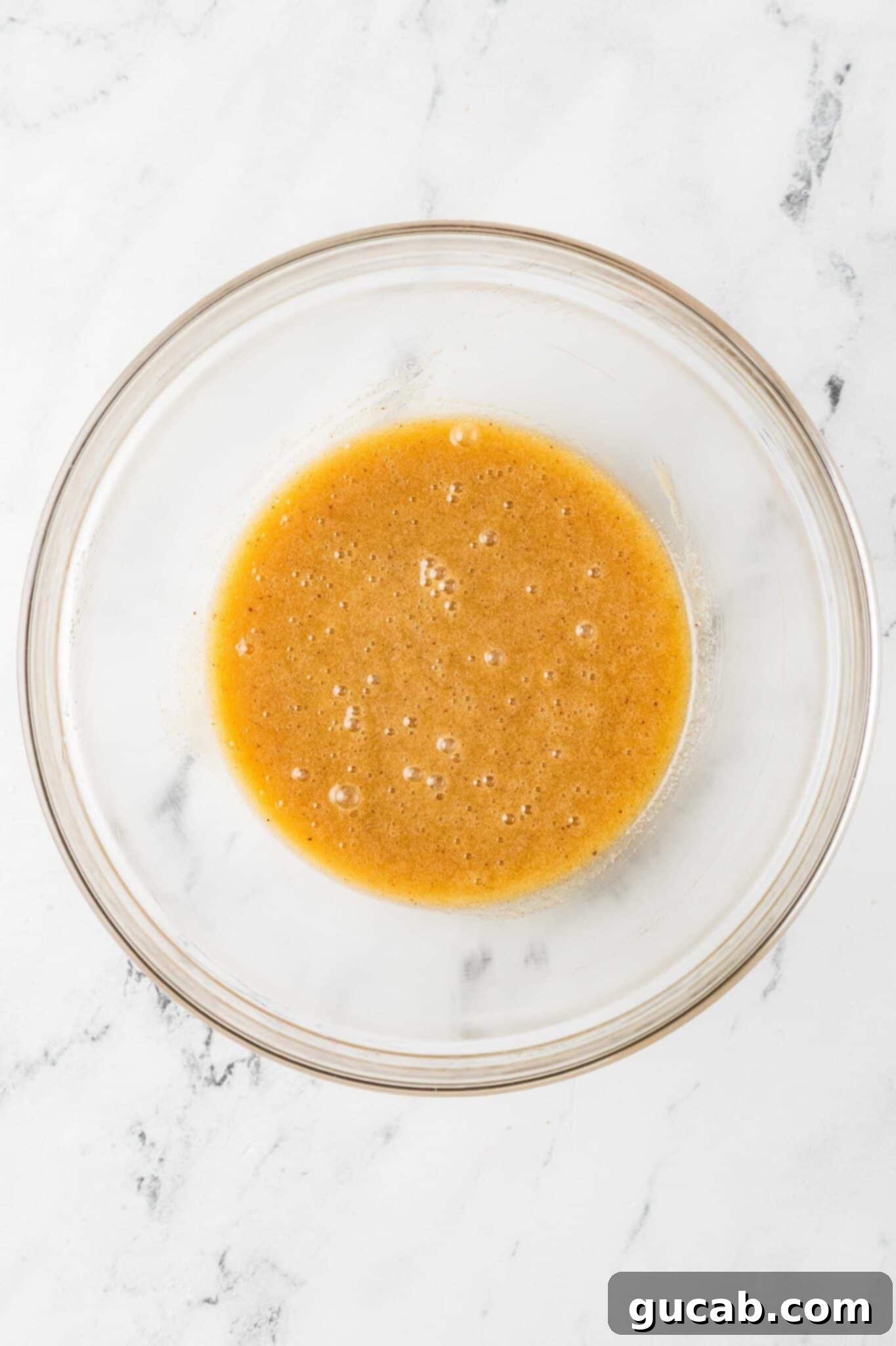 A smooth, golden mixture of sugar, egg, and browned butter in a bowl, ready for the dry ingredients.