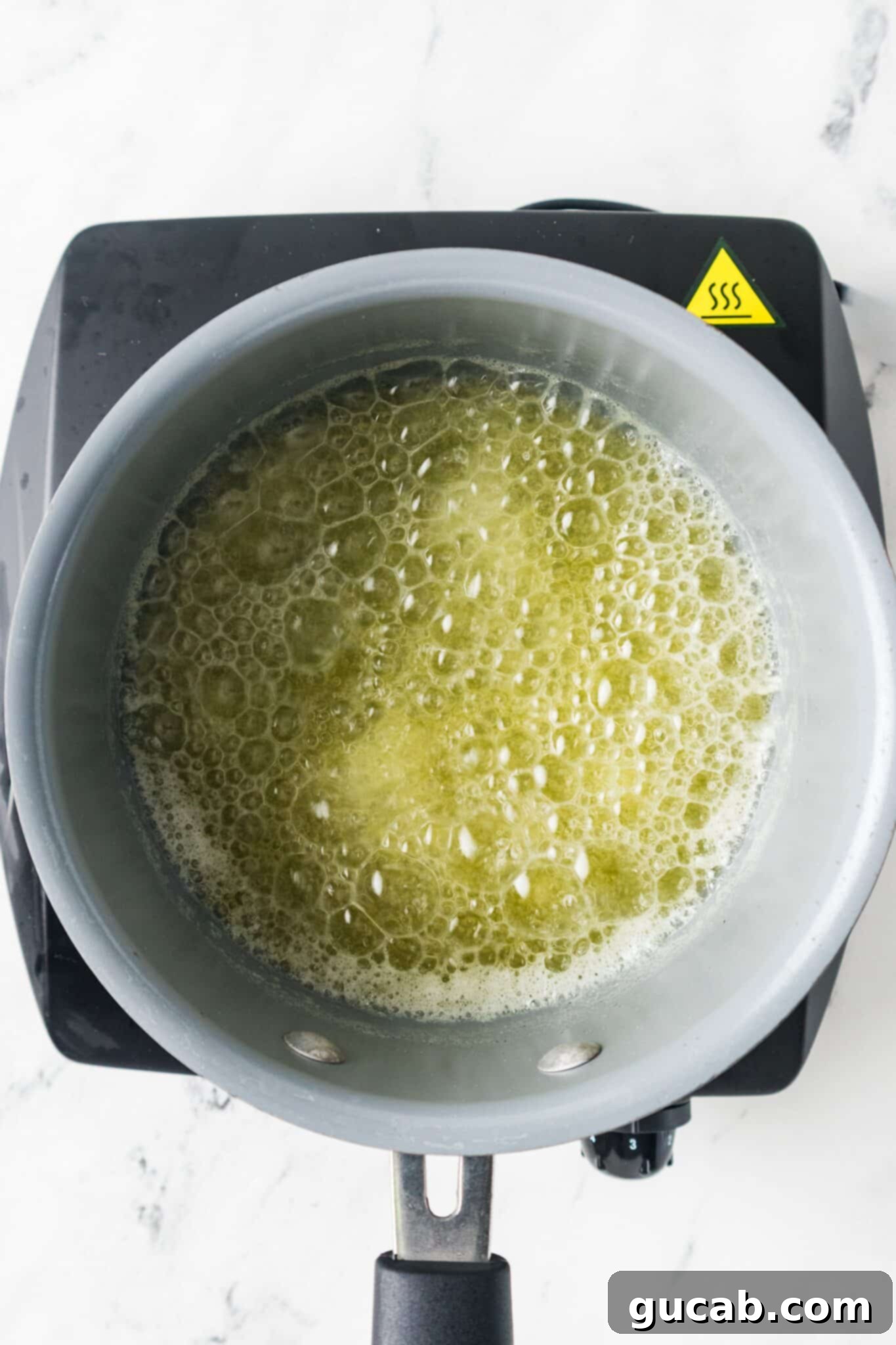 A pot of melted butter gently bubbling, indicating the beginning of the browning process.