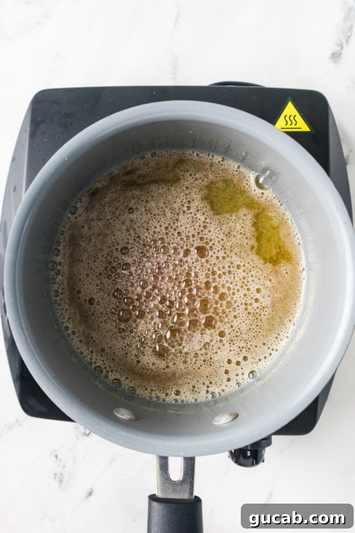 A pot of perfectly browned butter with amber liquid and golden-brown milk solids at the bottom.