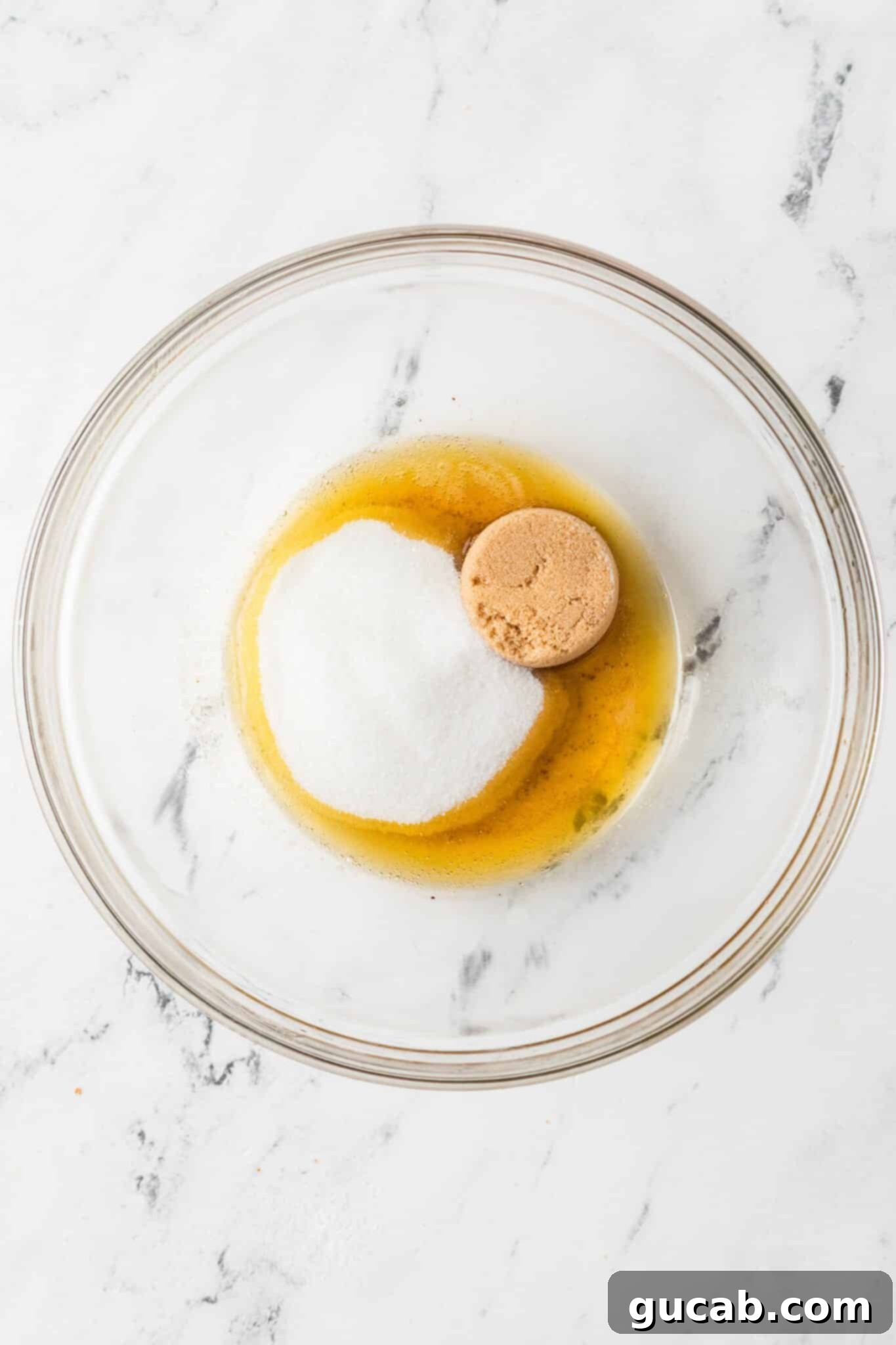 A bowl containing browned butter, granulated sugar, and brown sugar before mixing.