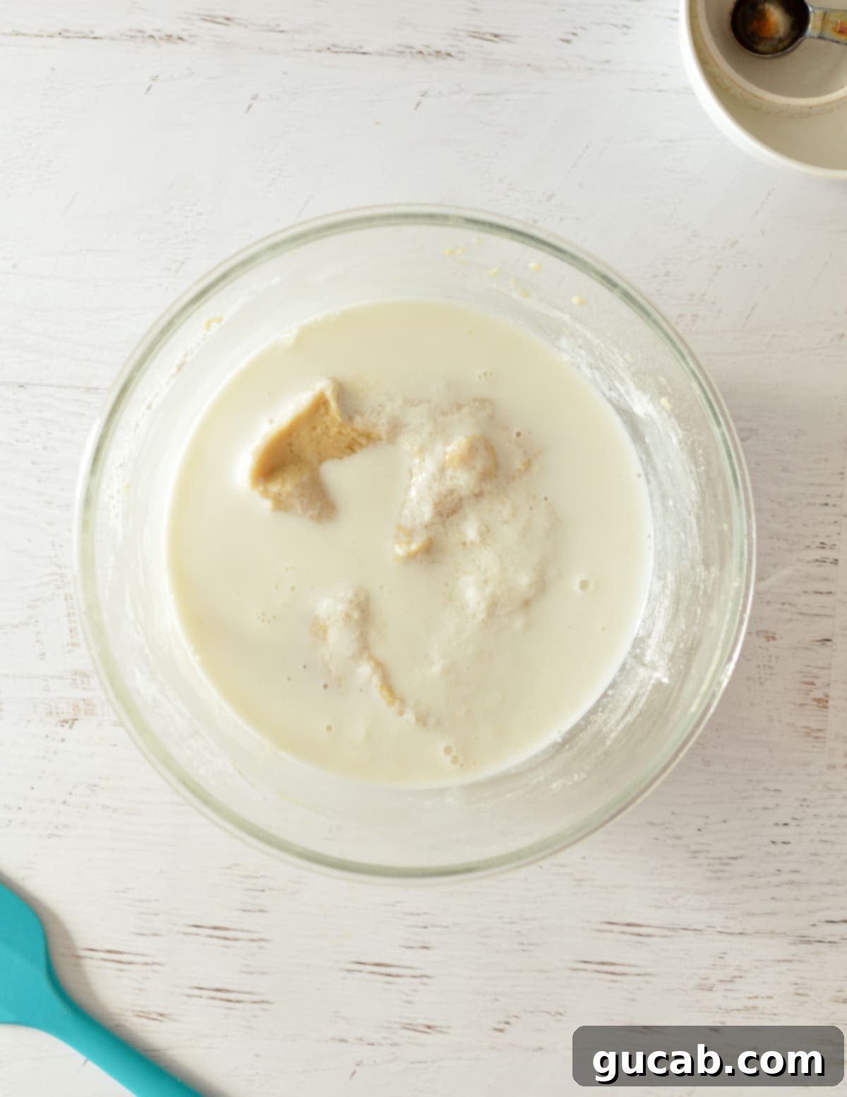 A bowl of cake batter with the milk and vinegar mixture added on top.